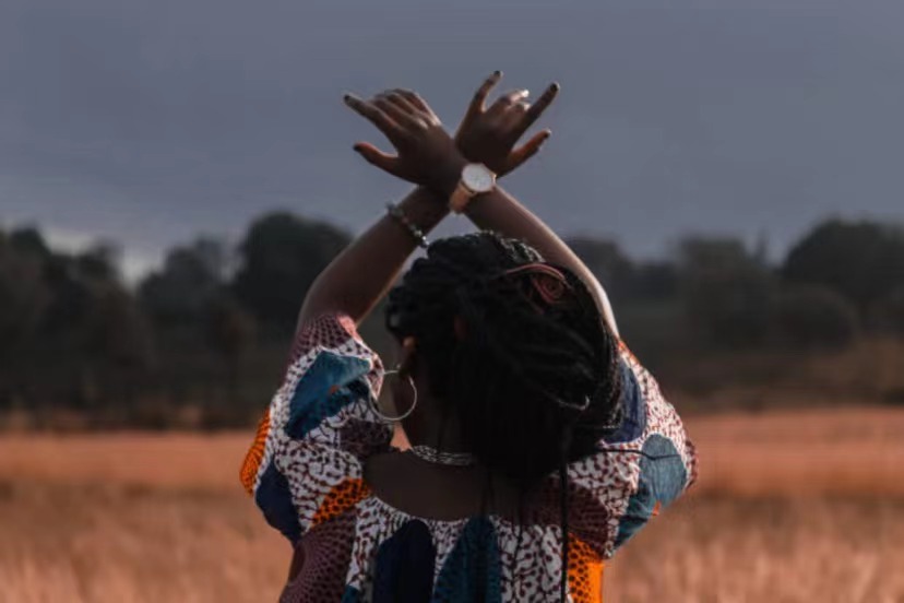 African woman with hands up in the air.