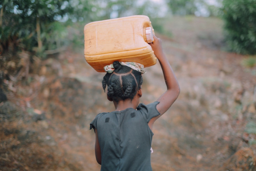 African girl with jerrycan over her head.