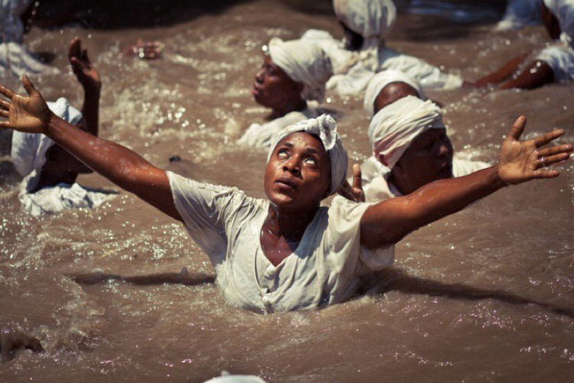 An african woman worshipping a god in water.