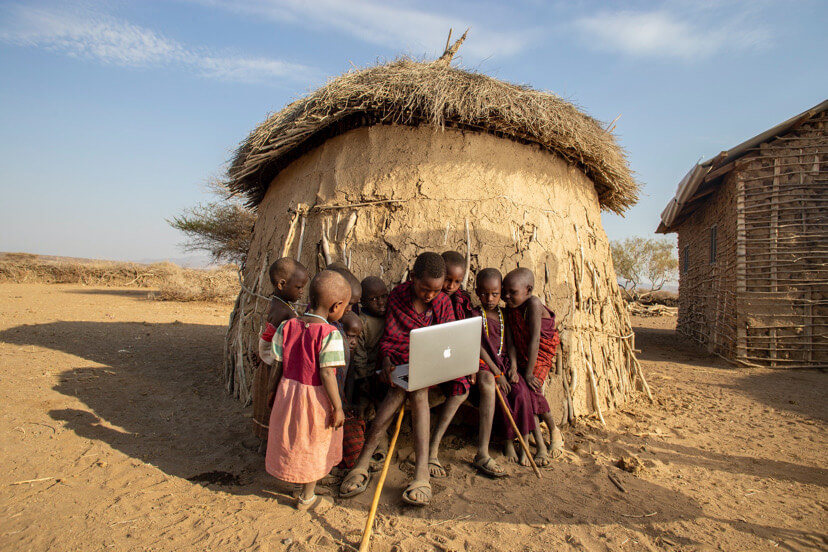a group of young local boys using a laptop.