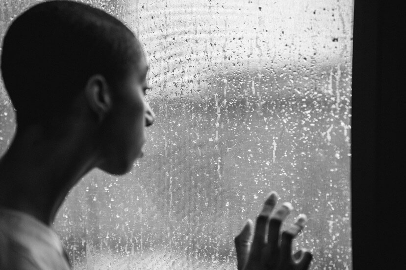 African woman staring outside a window