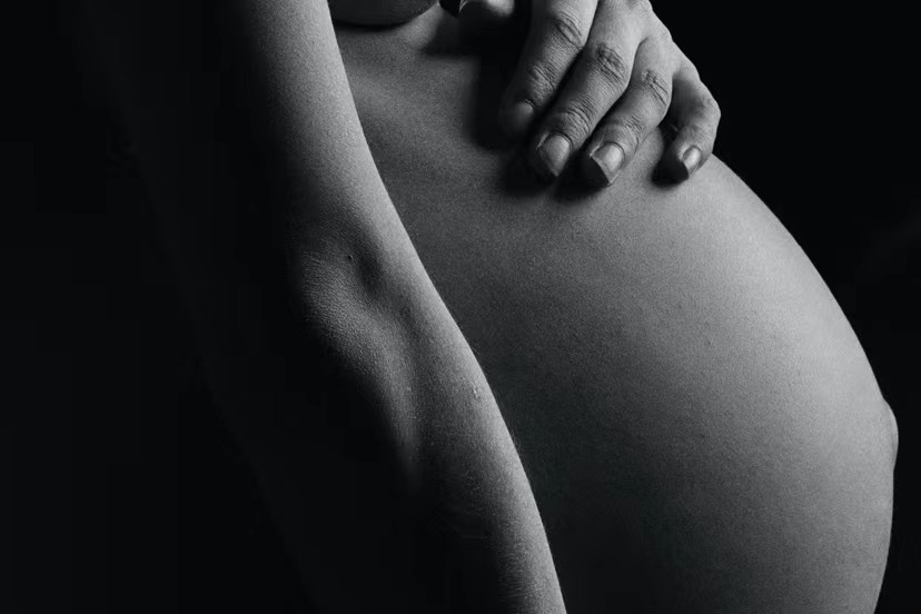 A pregnant woman holding her tummy.