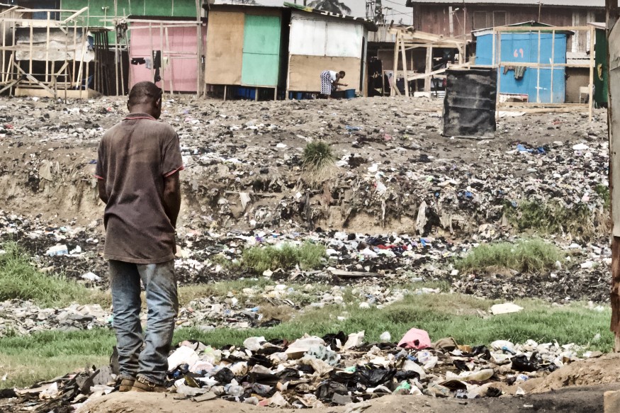 An African man standing over trash.
