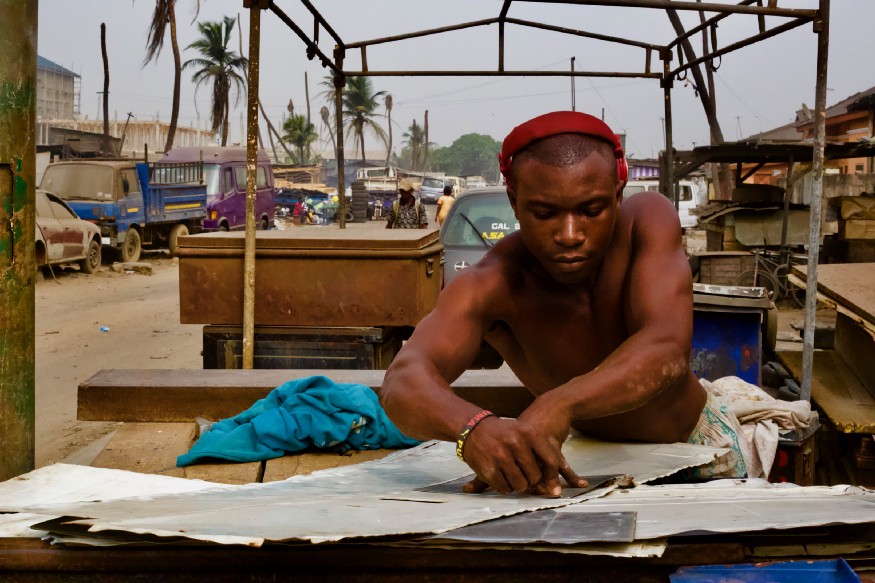 An African man working with metal scraps.