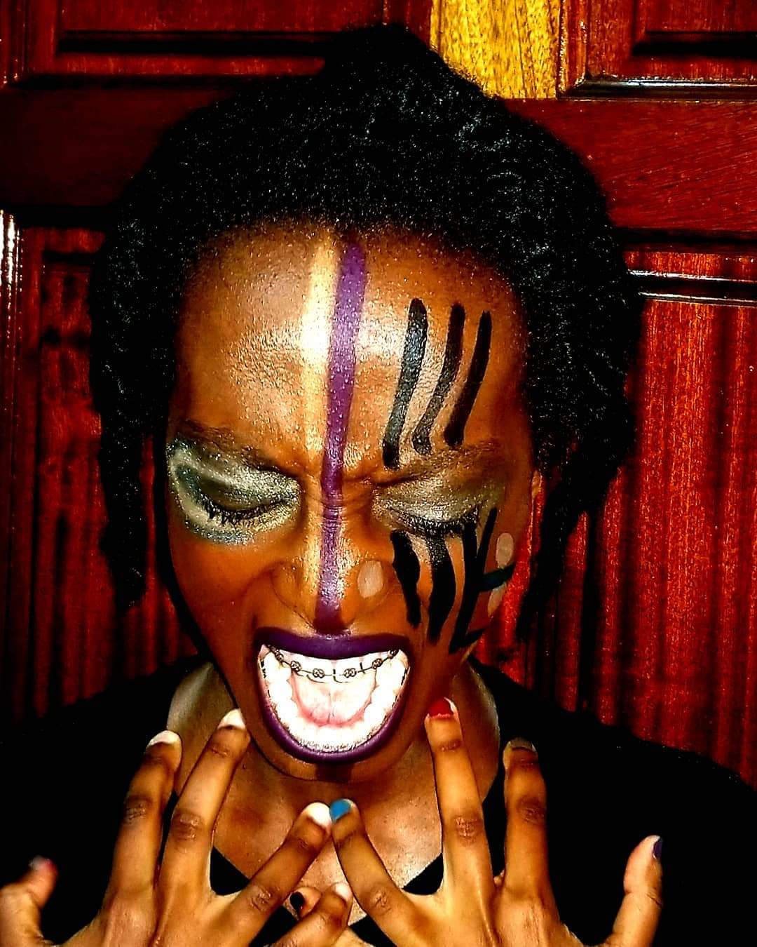 An African woman screaming with make-up art on her face.